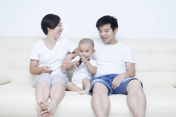 Ευτυχισμένη κινεζική οικογένεια κάθεται στον καναπέ - Φωτογραφία, εικόνα