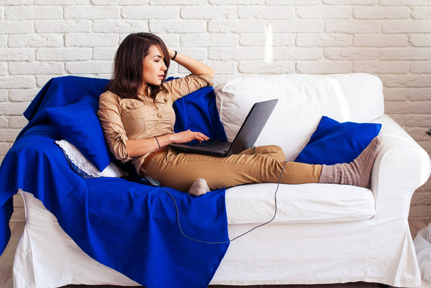 Una freelance che lavora a casa per un portatile. La ragazza sul divano con un portatile. Una studentessa con un computer portatile
 - Foto, immagini