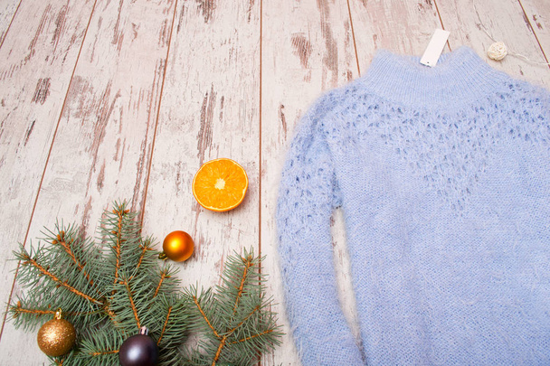 Weihnachtskonzept blauer Strickpullover mit Anhänger, Fichtenzweig mit Ornamenten, orange. Raum für Text - Foto, Bild