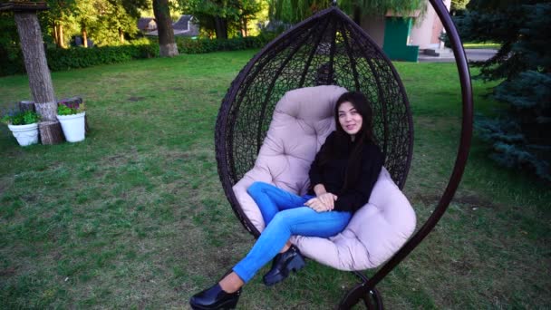 Attractive Lady Relaxes in Armchair, Looks Around and Smiles, Straightens Hair and Talks With Someone in Park Outdoors. - Imágenes, Vídeo