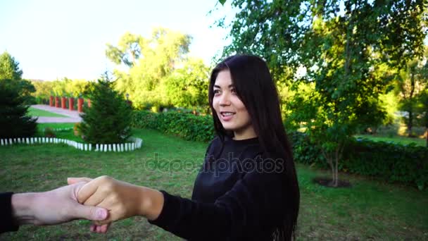 Pretty Female sostiene la mano del tipo y se comunica con su novio, sonríe y ríe, mira la cámara y posando. Chica en Green Park al aire libre
. - Imágenes, Vídeo