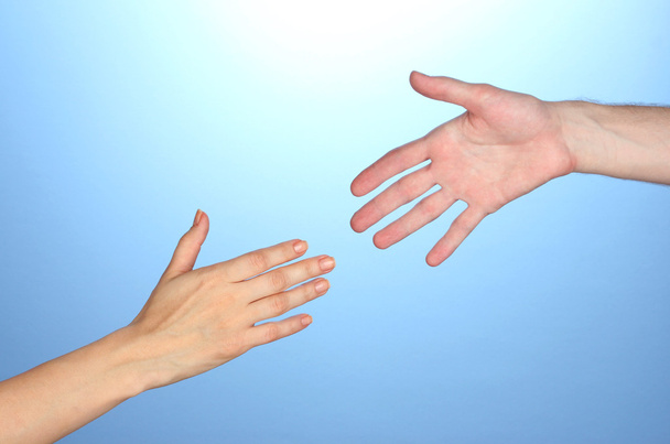 Women's hand goes to the man's hand on blue background - Valokuva, kuva