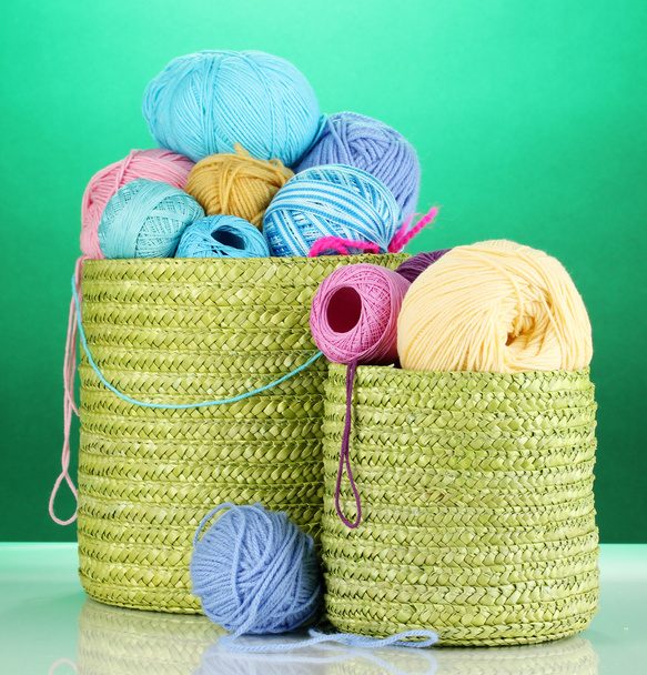 Colorful yarn for knitting in green basket on green background - Фото, изображение