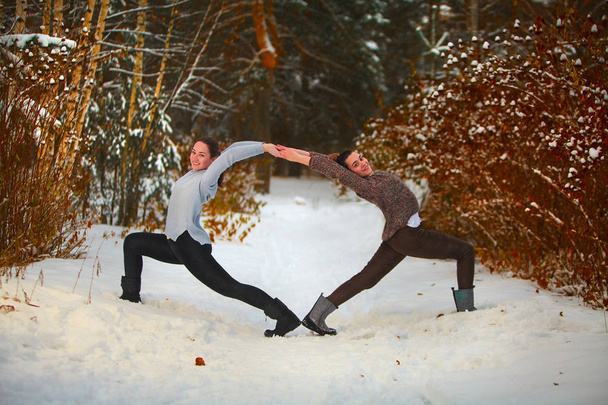 two beautiful women  doing yoga outdoors in the snow  - Photo, Image