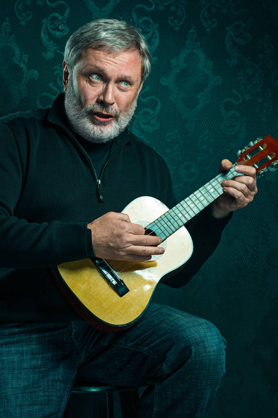 Studio portrait of senior man with guitar. - Fotografie, Obrázek