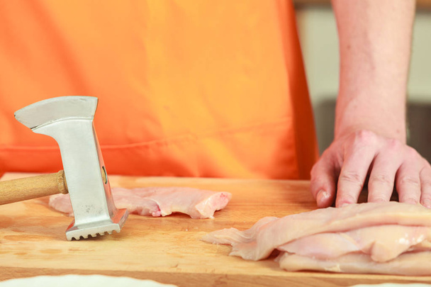 Man beating chicken meat on wooden board - Zdjęcie, obraz