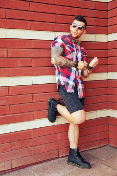 Young tattooed man posing on brick wall background - Foto, Imagem