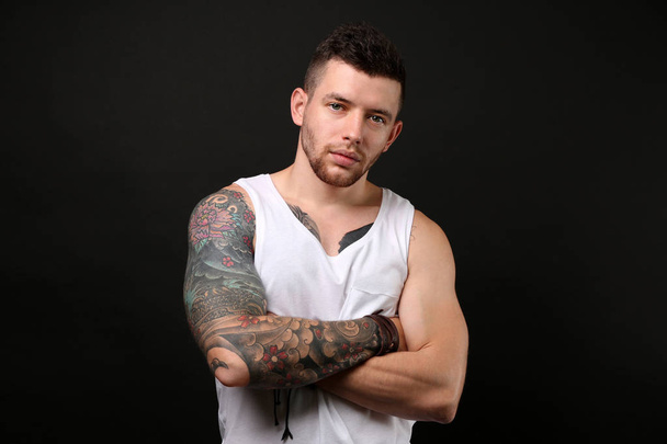 Young tattooed man posing on dark background - Fotoğraf, Görsel