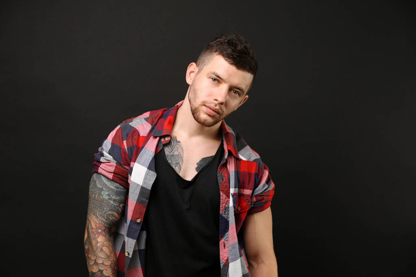 Young tattooed man posing on dark background - Φωτογραφία, εικόνα