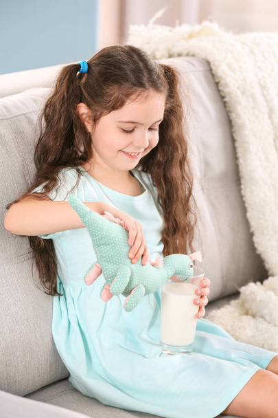 Linda niña alimentación dinosaurio juguete con leche
 - Foto, Imagen