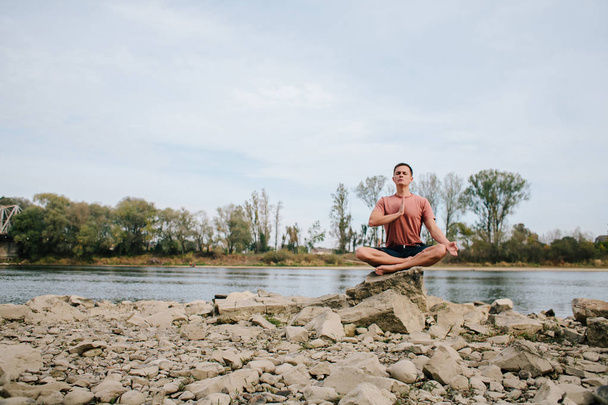 ο άνθρωπος πρακτικές γιόγκα στην όχθη του ποταμού  - Φωτογραφία, εικόνα