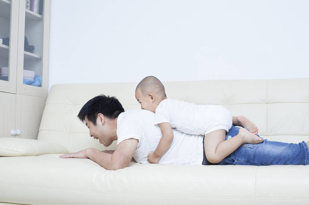 Chino padre e hijo jugando en sofá
 - Foto, Imagen