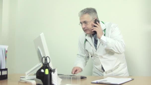 De arts is gealarmeerd op de werkplek op de computer te typen iets en praten over de telefoon. - Video