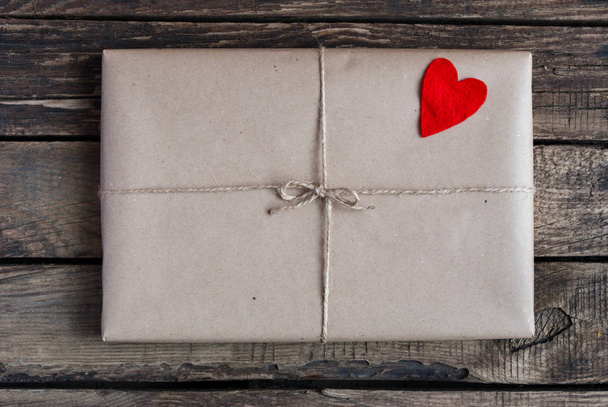 Gift wrapped in a kraft paper with red hearts - Foto, afbeelding