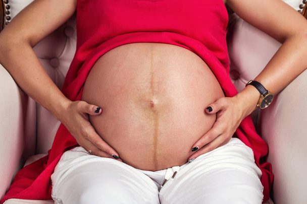 Kuva raskaana olevasta naisesta vatsa. Kädet halaavat raskaana olevaa vatsaa. lähikuva ihmiskäsistä, jotka pitelevät raskaana olevaa vatsaa. Raskaana oleva nainen halaa vatsaansa. Raskaus. Raskauden käsite
 - Valokuva, kuva