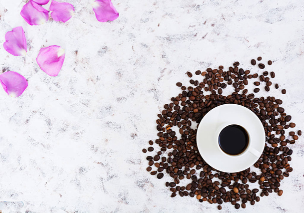 Coffee cup, coffee beans and rose petals on white background. Top view. Flat lay - 写真・画像