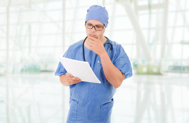обеспокоенный доктор смотрит на свои записи, в больнице
 - Фото, изображение