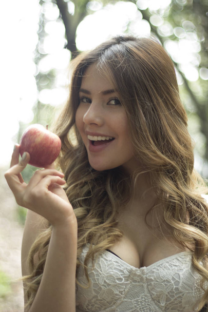 Beautiful girl showing an apple - Fotó, kép