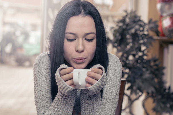 Young brunette Caucasian woman is drinking tea at a bar. - Photo, Image