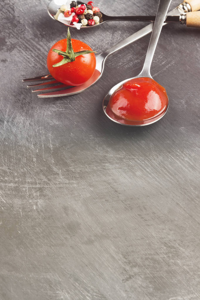 Molho de tomate, cereja, temperos em garfo e colheres em um backgr escuro
 - Foto, Imagem