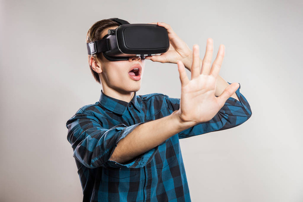 hombre divertido emocional con gafas de realidad virtual. Retrato de estudio del diseñador de videojuegos con auriculares VR. estudio disparo aislado sobre fondo gris
. - Foto, imagen