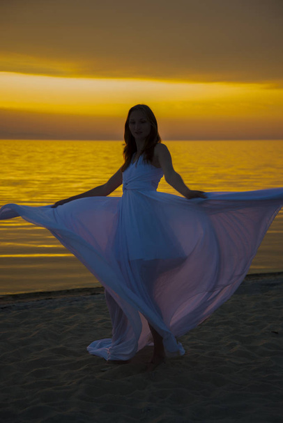 Beautiful girl in a long white dress walking on the seaside. - Fotografie, Obrázek
