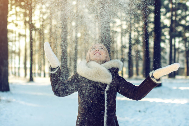 attractive woman throws up snow into the air at sunset - Zdjęcie, obraz
