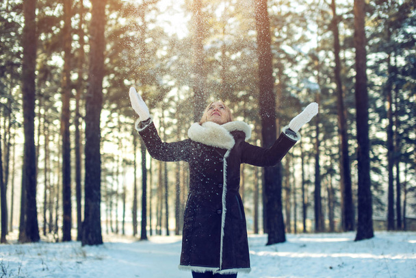 viehättävä nainen heittää lunta ilmaan auringonlaskun aikaan
 - Valokuva, kuva