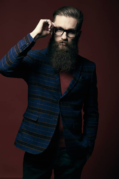 Portrait of serious stylish man with beard and glasses in dark studio - Valokuva, kuva