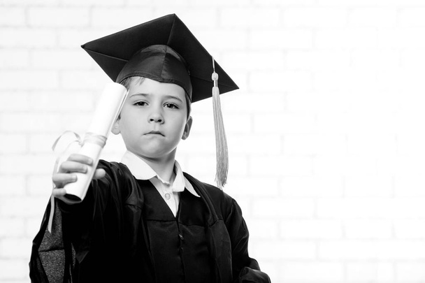 Garçon de l'école primaire en coupe et robe posant avec diplôme
 - Photo, image
