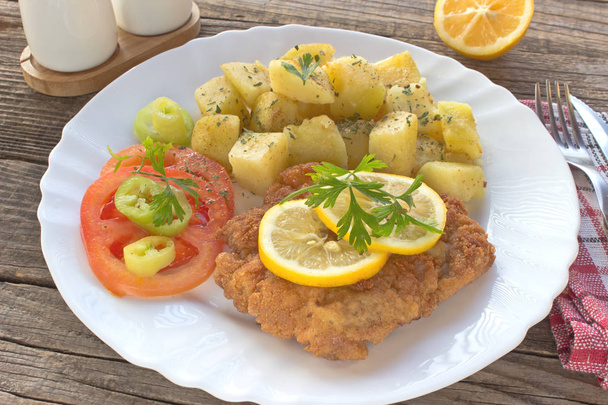 Wiener schnitzel with potatoes in plate on table - Photo, Image
