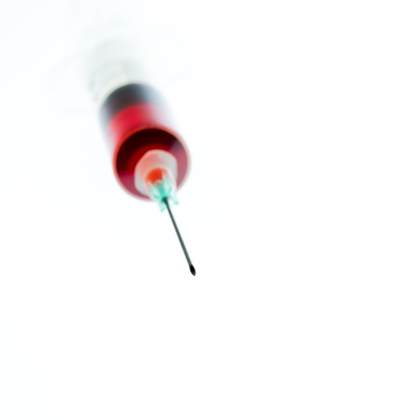 Needle and syringe containing red liquid. - Zdjęcie, obraz