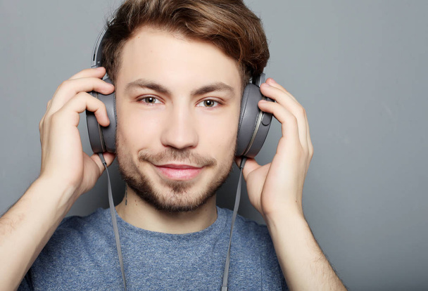 Happy young stylish man  adjusting his headphones ad smiling wh - Photo, image