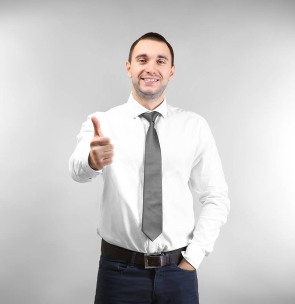 Handsome man showing thumb up sign, on light background - Photo, image