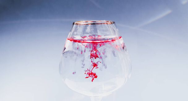 Wine glass filled with red and yellow ink - Zdjęcie, obraz