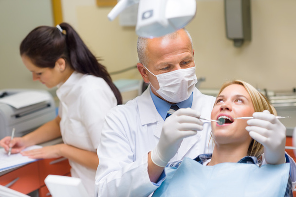 Dentist doing procedure on young patient woman - Foto, imagen