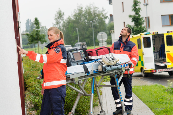 Paramedics with medical equipment ringing doorbell - Foto, imagen