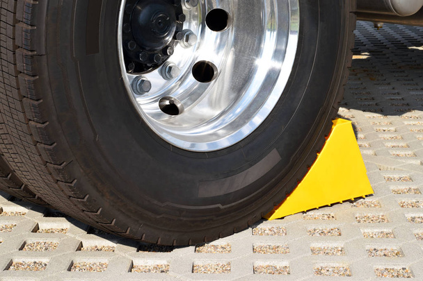 Gelber Unterlegkeil am Steuer eines geparkten Lastwagens  - Foto, Bild