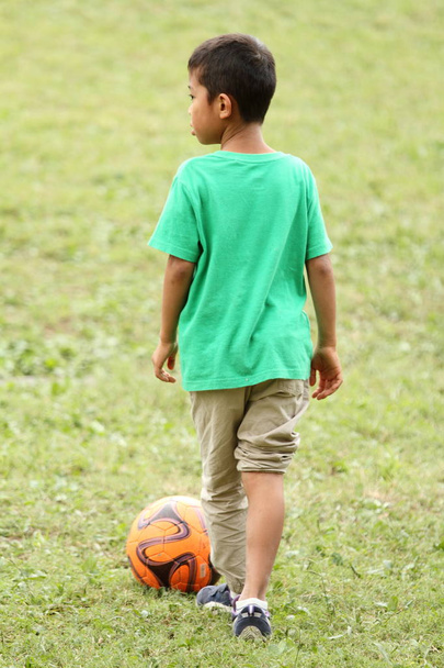 Ιαπωνικό αγόρι παιχνίδι με μπάλα ποδοσφαίρου (βαθμού πρώτα στο Δημοτικό σχολείο) - Φωτογραφία, εικόνα