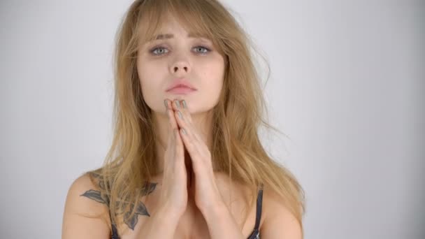 Συναισθηματική ελκυστική νεαρή γυναίκα με θλιμμένο πρόσωπο, της έσφιγγα τα χέρια σε δέηση ή προσευχή - Πλάνα, βίντεο