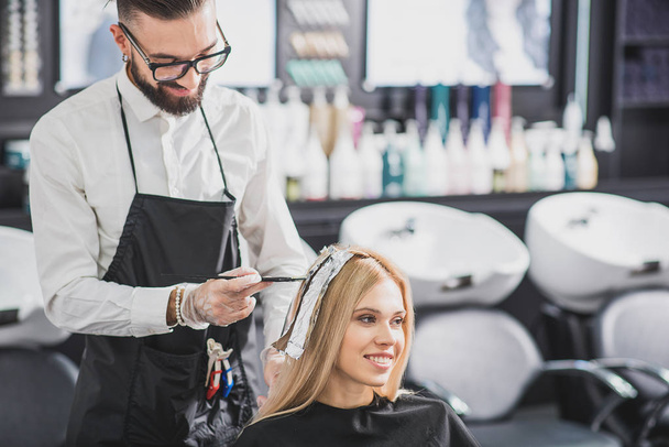 Smiling stylist is dying long hair - Photo, Image