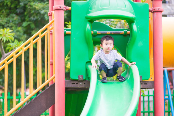 Little Asian kid playing slide at the playground - Foto, Imagen