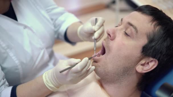 female dentist making procedures to male patient at clinic, close up - Felvétel, videó