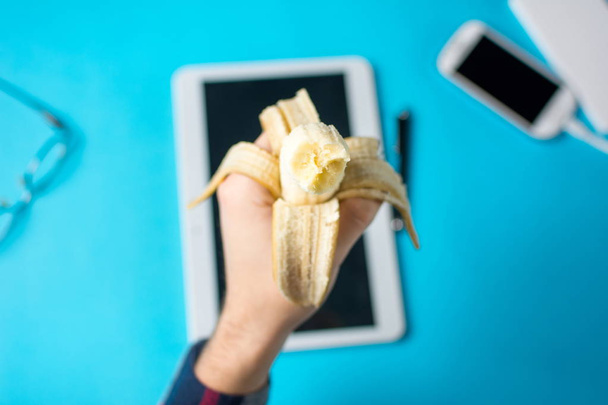 Homem segurando uma banana sobre um tablet
 - Foto, Imagem