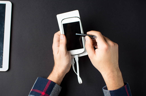 Erkek el beyaz bir cep telefonu tutan bir güç bankaya bağlı - Fotoğraf, Görsel