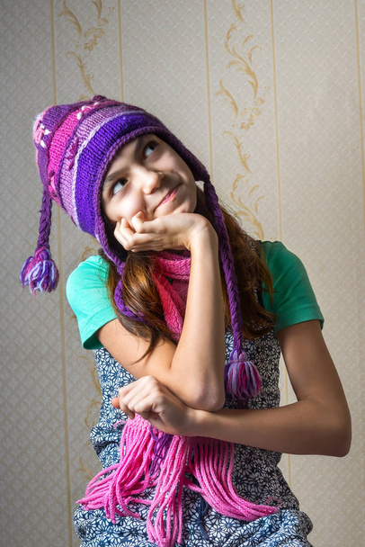 Portrait of a 11 year old girl in a shirt and a knitted hat and scarf, looking up pensively. - Photo, Image