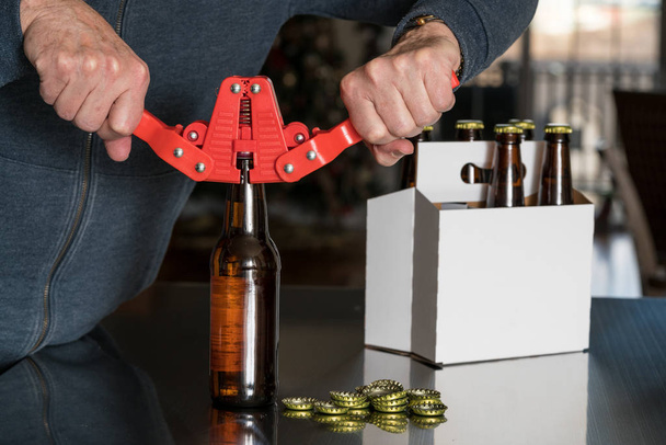 Hombre usando tapón para poner tapas de metal en la botella de cerveza
 - Foto, imagen