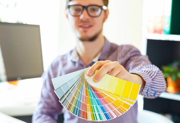 Hombre joven mirando a una paleta de pintura de color
 - Foto, Imagen