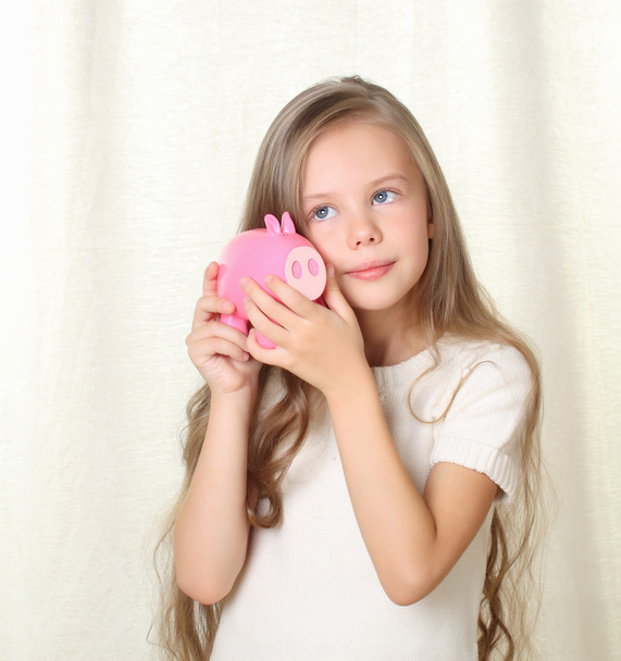 Littlr blond girl looking on piggy moneybox - Fotoğraf, Görsel