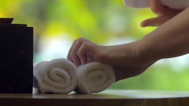 Posizionamento di asciugamani freschi con fiore sul tavolo in spa
 - Filmati, video